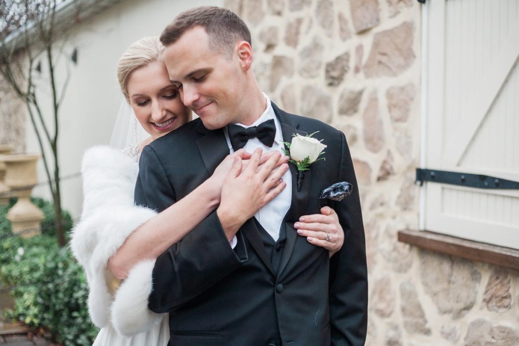 Bride in white fur hugging groom in black tux at the Inn at Leola Village by the Jepsons