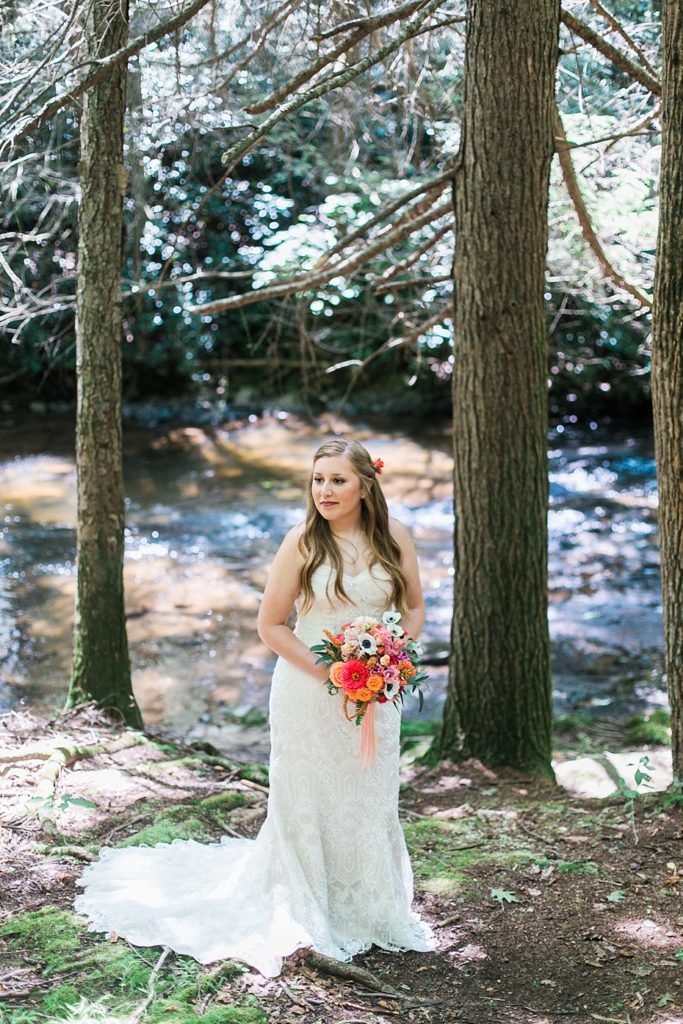 bride gazing at groom while standing by stream in the forest