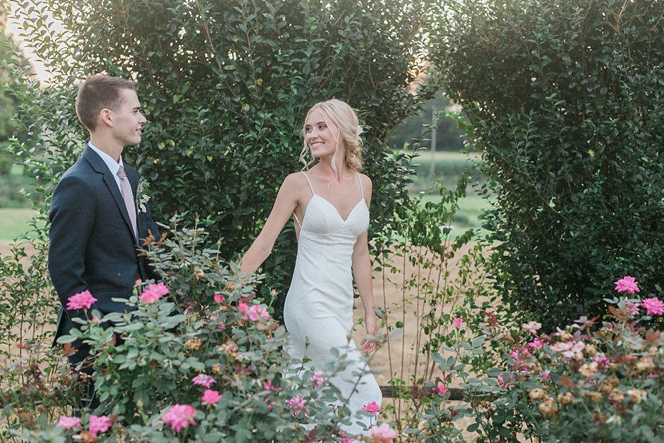 Bride and groom walk through rose garden at White Chimneys wedding by the Jepsons