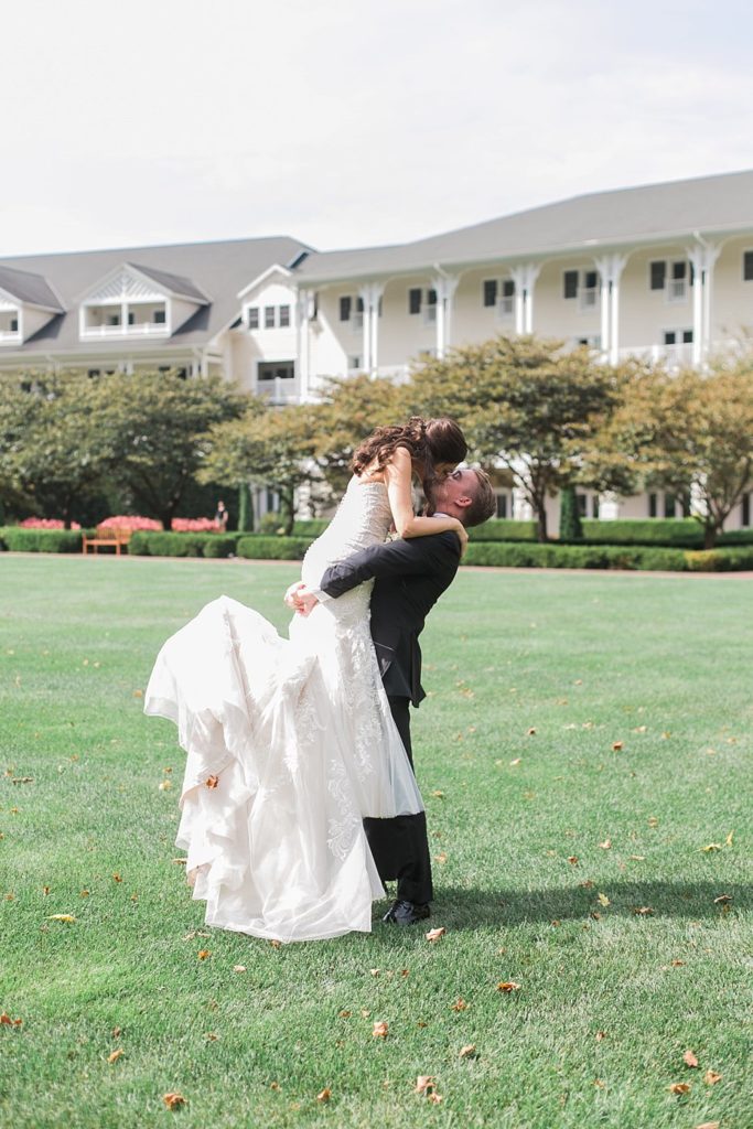 Groom lifts bride outside the Omni at Bedford Springs