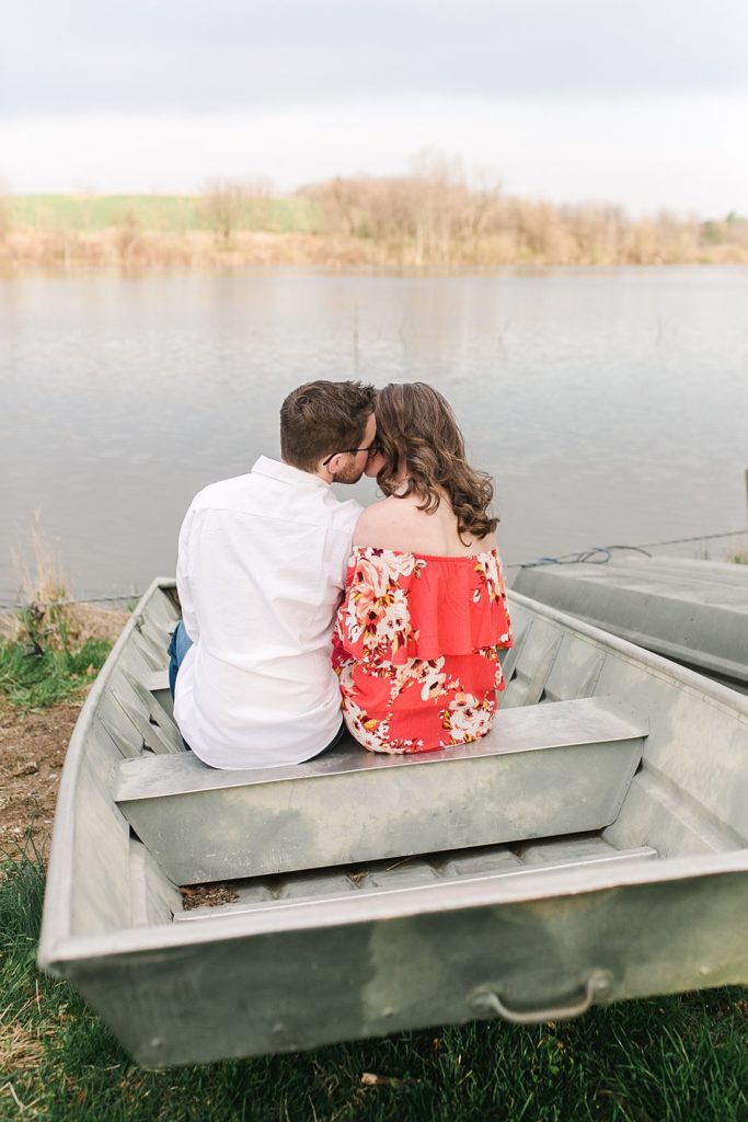 Couple kisses in fishing boat on shores of Speedwell Forge Lake in Pennsylvania.