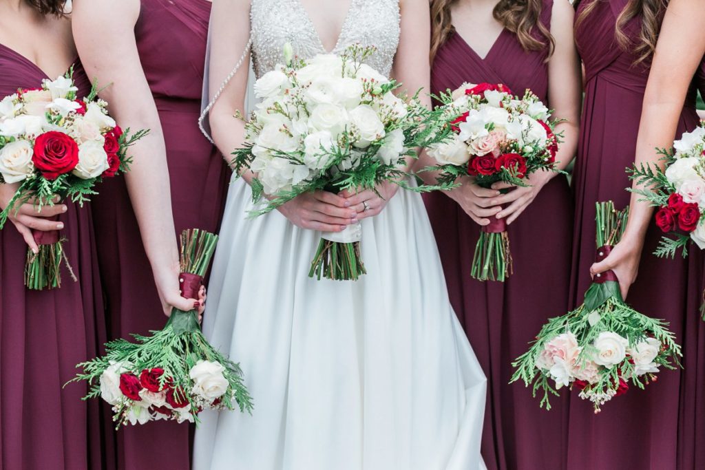 Bridesmaids holding white and red florals at the Inn at Leola Village by the Jepsons