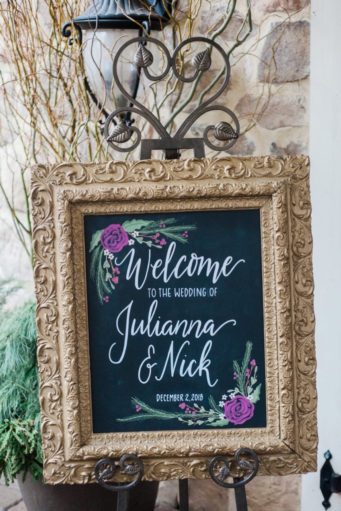 hand-lettered calligraphy welcome sign for wedding with purple floral designs by the Jepsons