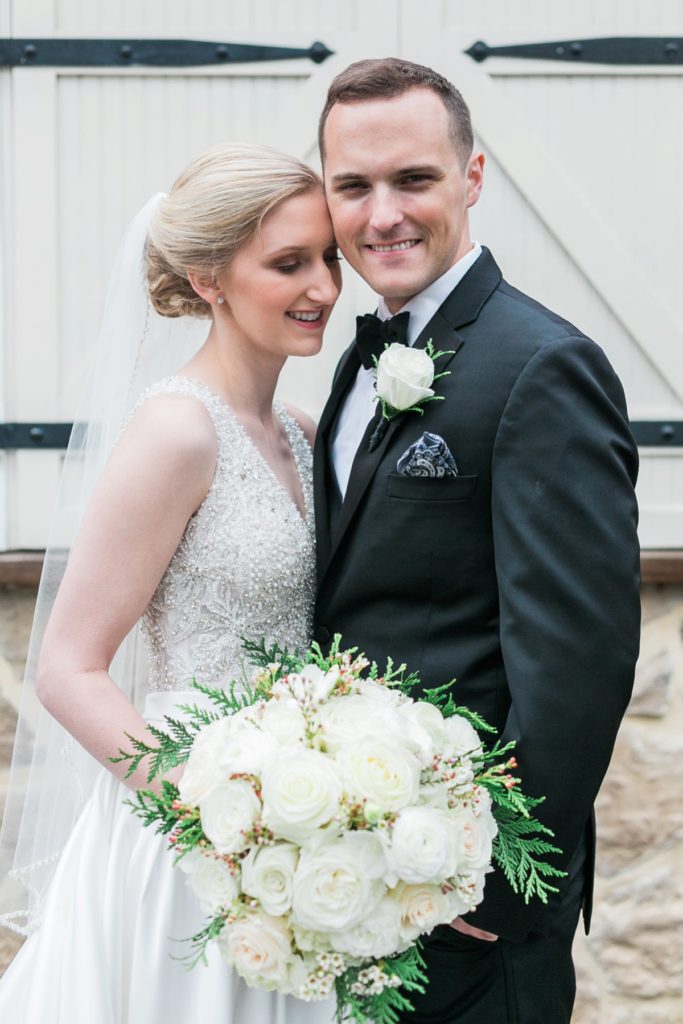 Bride and groom smiling with white floral bouquet at the Inn at Leola Village by the Jepsons