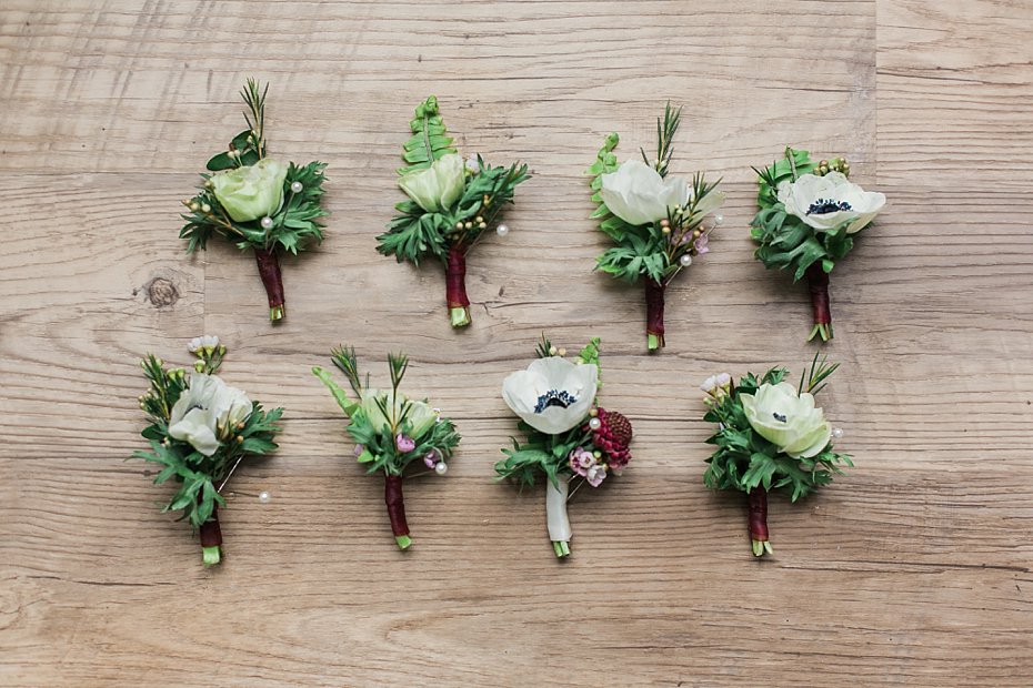 green and burgundy boutonnieres by Pocketful of Posies on wood planks