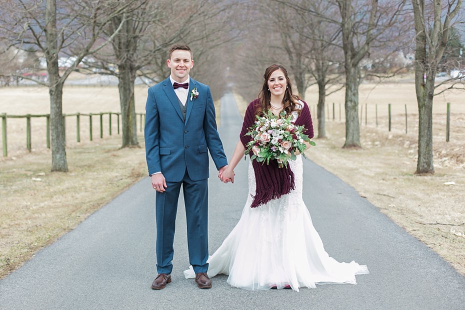 bride and groom with burgundy and white bouquet by the Jepsons