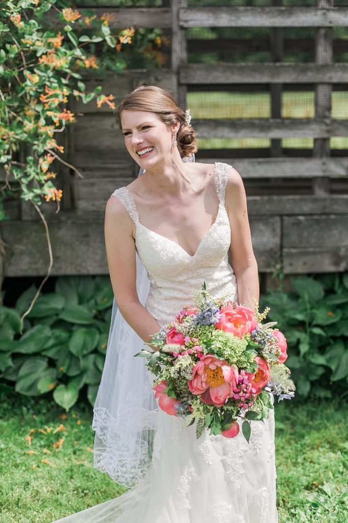 Bride laughs while holding coral peony bouquet made by Pocketful of Posies