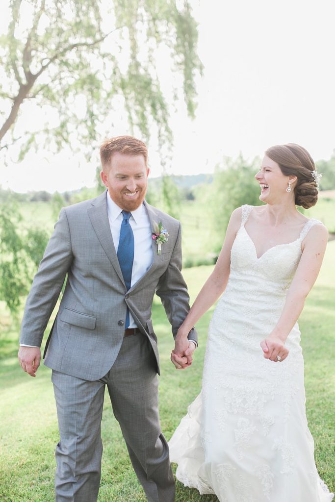 Bride and groom laugh by the stream at Gillbrook Farms