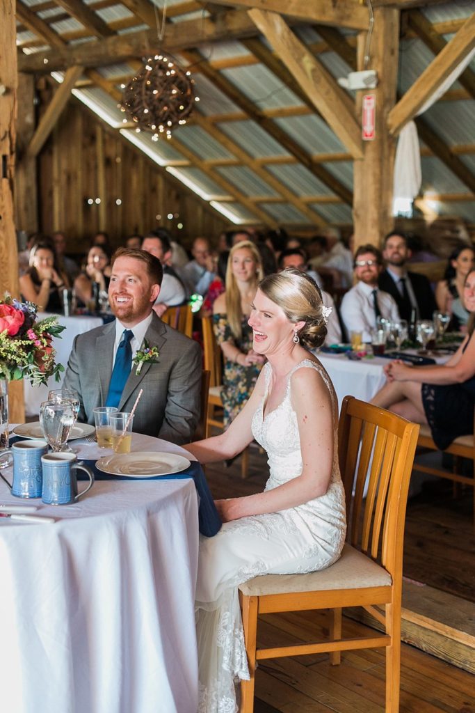 Bride and groom laugh during reception in the barn at Gillbrook Farms