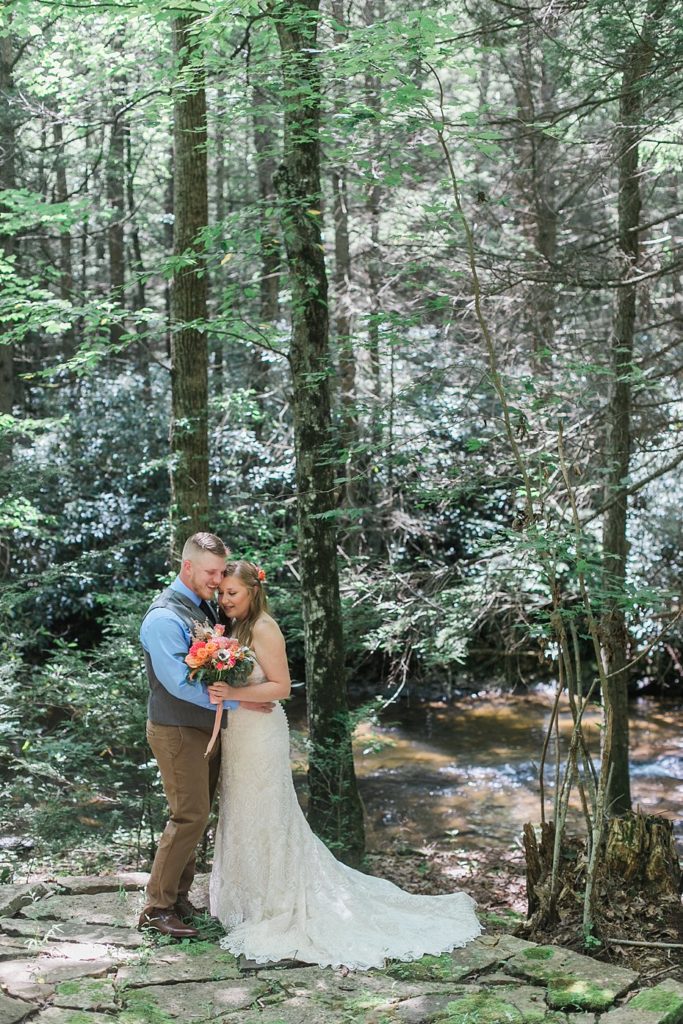 bride and groom hugging by stream at Fern Hill