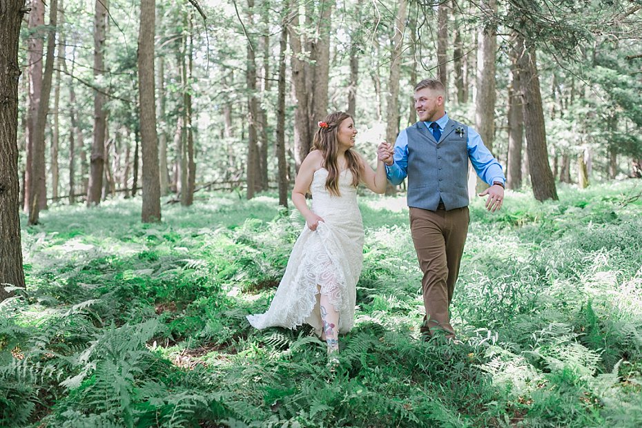 bride and groom joyfully walk through Pennsylvania forest