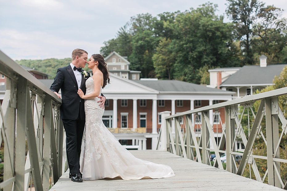 Bride and groom pose on bridge in front of the Omni at Bedford Springs Resort