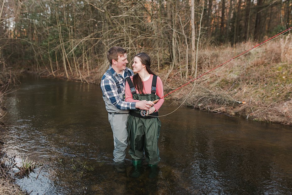 Couple wearing waders and fishing in Sinking Creek during Colyer Lake, PA engagement session