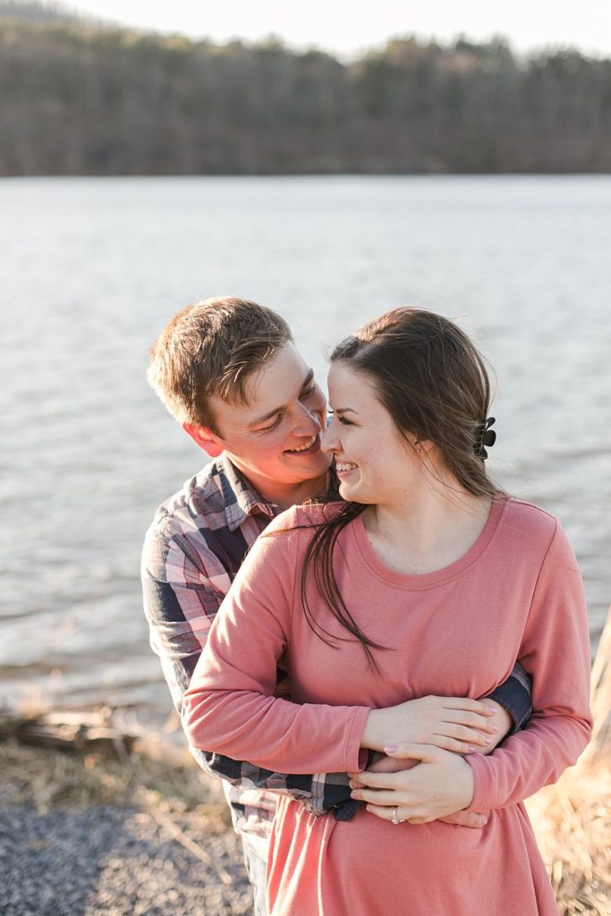 Couple hugging for engagement session on shores of Colyer Lake in central Pennsylvania