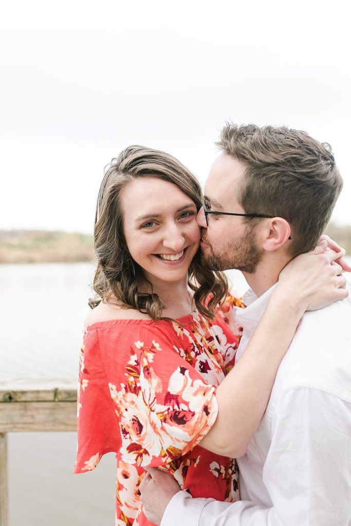 Groom kissing fiancée's cheek for engagement session at Speedwell Forge Lake.