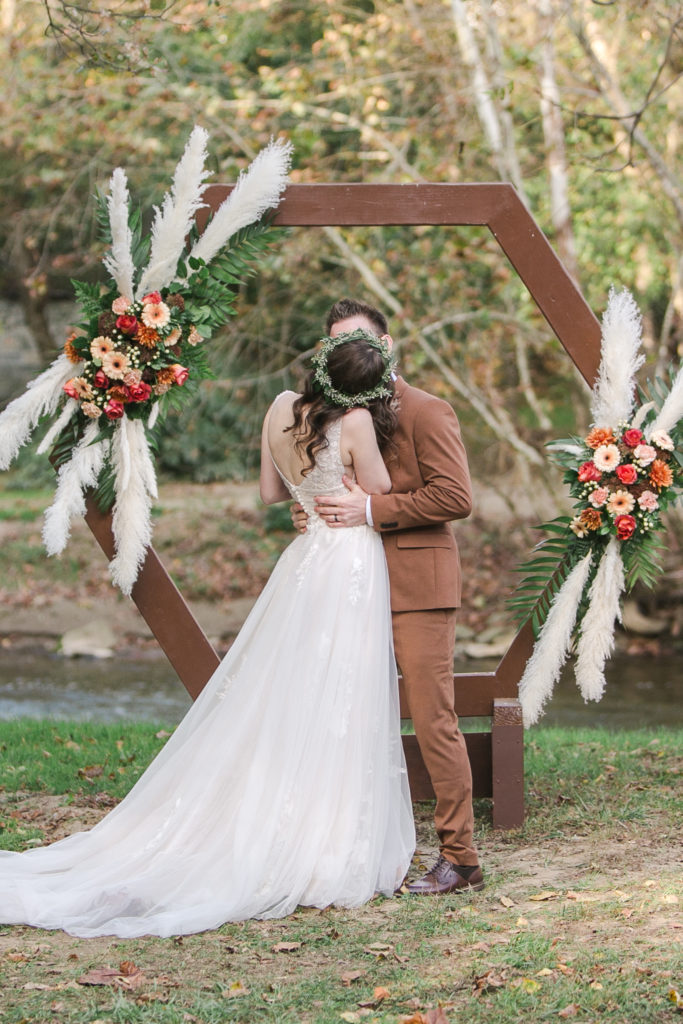 Bride and groom kissing in front of boho wedding altar at Sickman's Mill in Pennsylvania