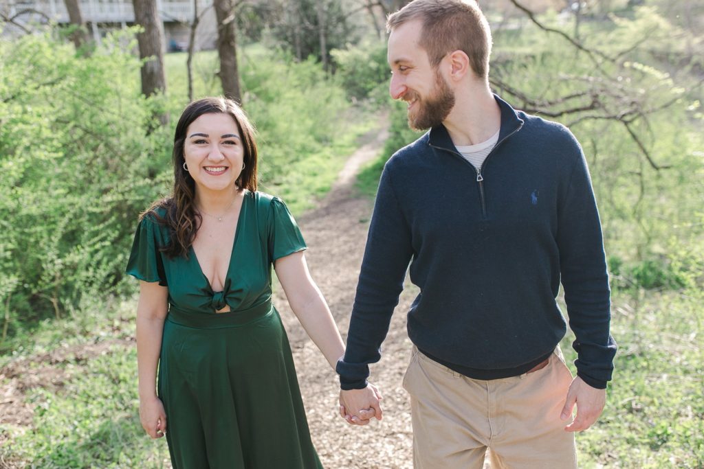 Engaged couple holding hands and walking on trail in State College, PA
