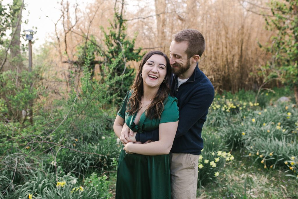 Couple laughing and hugging amid daffodils in State College, PA